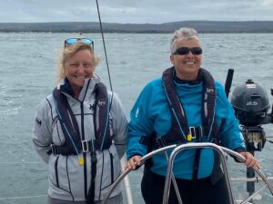 Pip Hare alongside day sailor Judith. Judith is steering and Pip supervising, both have wide smiles!