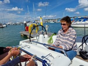 Visa-gb mate, Helen sitting opposite Ollie & Anil practicing her knot tying skills. Behind the boat is the pontoon.