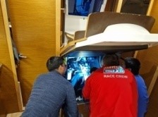 Engine check, the cover which also are the companionway steps lifts up to allow access to the engine. Ollie and Gareth, alongside skipper Mark, and kneeling down to inspect the engine.