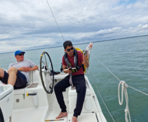 The stern of the boat looking towards the starboard wheel. Gareth is sitting concentrating on fishing while Billy has his feet up relaxing.