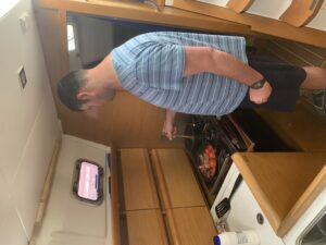 Brandon standing at the cooker, spoon in his right hand stirring the scrambled eggs, in a pan next to the eggs are tomatoes and bacon.