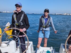 Dee at the Helm steering the boat witht he help of Jane Barnes