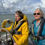 Anita at the Helm deep in though and feeling for the breeeze telling her which way to turn with 1st mate Jennie smiling into the camera