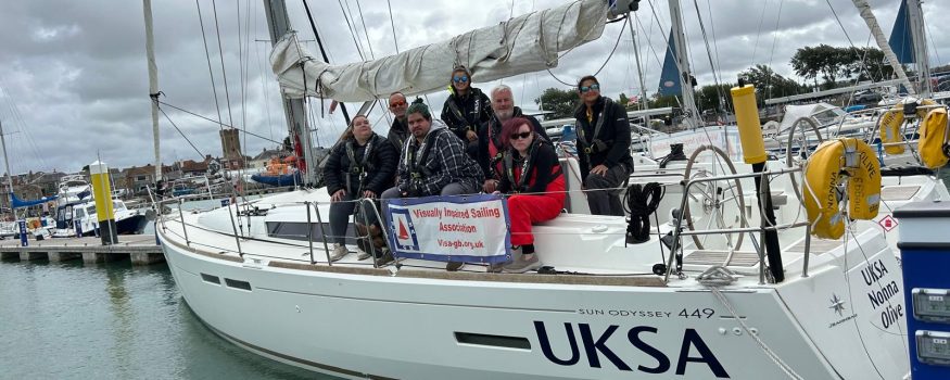 Photo of the UKSA boat with all of the crew lined up and looking at the camera in Yarmouth harbour. The visa-gb dodger is visible